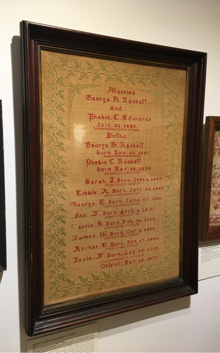 <h3>Rackett Family Genealogical Sampler</h3>
<br>
<p><strong>1876</strong></p>
<p><strong>Gift of Cora Demarest and Sally Wiggs</strong></p>
<br>
<p>This large genealogical sampler was most likely made as a Centennial project by one
of the eight children of George R. Rackett and Phebie C. Edwards who were married
(as stated on the sampler) on July 21, 1842. Phebie was just seventeen years old.
This is a fairly plain genealogical sampler but has careful stitching and a very
handsomely designed border. Many genealogical samplers are highly decorated, and
are often designed in the shape of a “family tree”. This sampler is a useful family
record that could be prominently displayed. It was probably made by one of the
daughters who had most likely honed her needlework skills by making more
traditional samplers.</p>